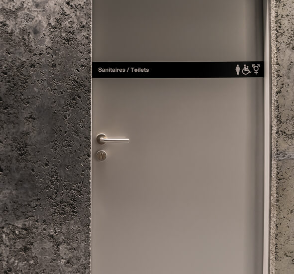 signalétique sur porte toilettes identifiée par impression numérique pictogrammes dans projet wayfinding studio