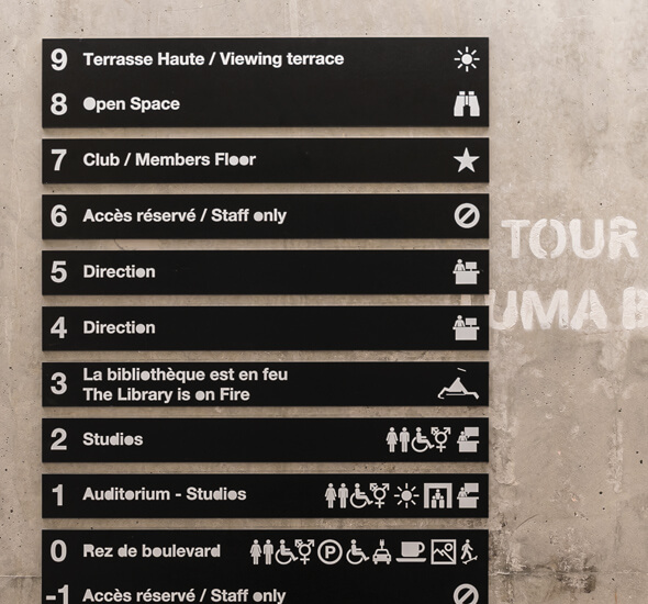 wayfinding studio plaque design noire avec texte et pictogramme blanc pour organiser et optimiser l’information signalétique à l’entrée bâtiment